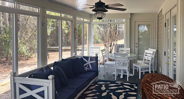 Bright sun shows through the windows of a sunroom decorated in white and navy blue with a nautical theme.