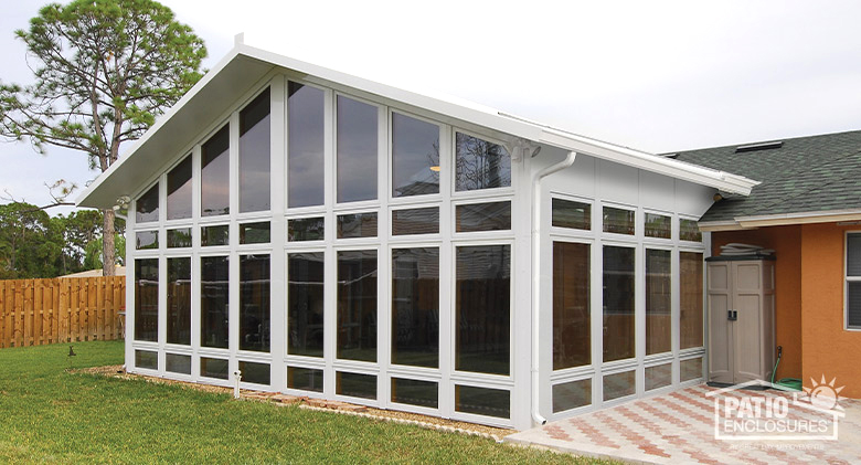 A large gable-roofed sunroom with glass wings, glass knee wall, and transoms.