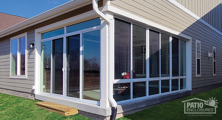 : A corner patio enclosed with a white-framed sunroom with glass knee wall.