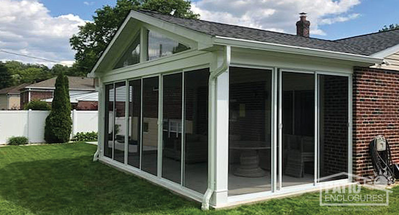 A screen room with shingled gable roof and glass wings in the peak and floor-to-ceiling sliding screen doors.