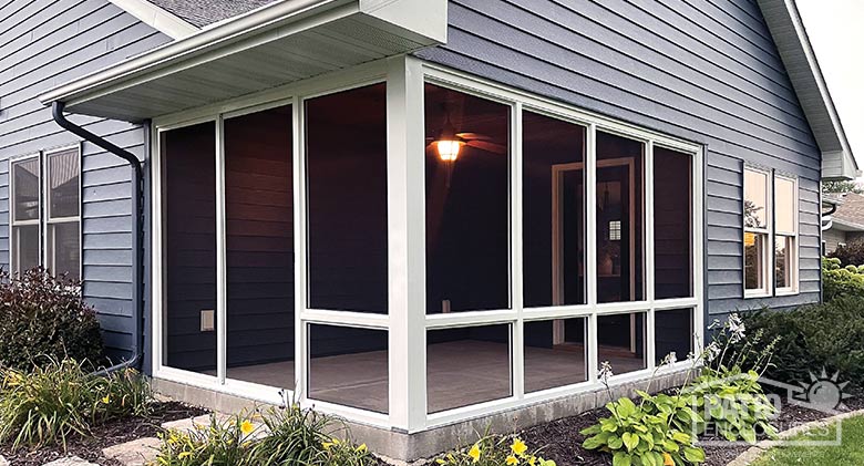 A screened corner patio with white frame and screened knee walls.