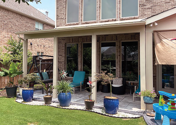 A backyard view of a family patio cover featuring lush plants, swings, and comfortable lounging chairs.