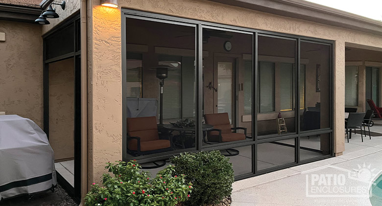 The exterior of a screen-enclosed patio on a tan stucco home with lights mounted above the room.