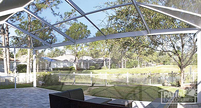 The interior of a white screened pool enclosure showing a view of the backyard through an extreme view screened wall.