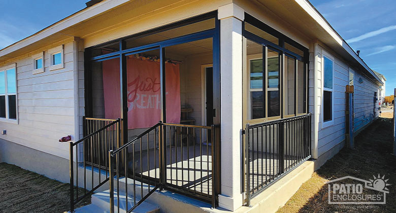 A brown lanai screen porch with picket railing system on the corner of a house.